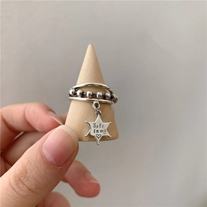 Détail macro d'une bague triple en argent S925 avec pendentif étoile et gravure