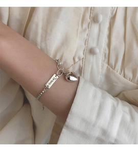 Détail du bracelet en argent S925 avec pendentif cœur et gravure Lucky girl au poignet