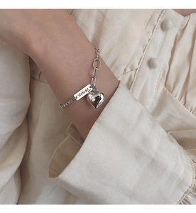 Détail du bracelet cœur en argent S925 avec gravure Lucky Girl porté au poignet