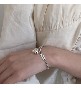 Détail du bracelet cœur en argent S925 avec plaque gravée Lucky Girl sur le poignet