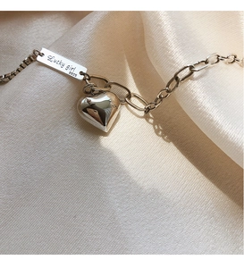 Détail de la chaîne en argent S925 avec plaque Lucky Girl et breloque coeur poli