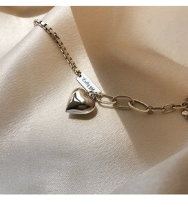 Macro de la breloque cœur en argent S925 et étiquette Lucky Girl sur tissu satiné