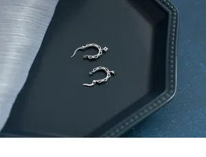 Macro shot of S925 silver lace hoop earrings with small zircon on a dark textured tray