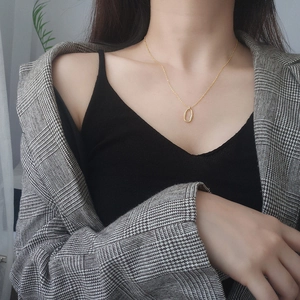 Minimalist s925 silver necklace with irregular oval pendant worn by model over grey blazer