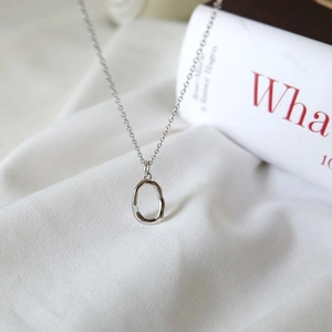 Close-up of minimalist S925 sterling silver necklace with irregular oval pendant detail