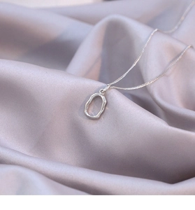 Irregular oval silver necklace detail on elegant purple silk fabric background