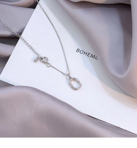 Close-up of minimalist S925 silver necklace with irregular oval pendant on silk fabric