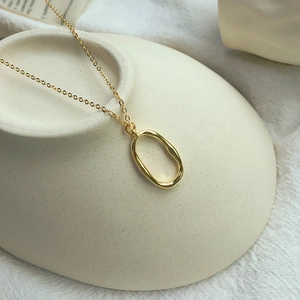Minimalist S925 silver necklace with an irregular golden oval pendant on ceramic base
