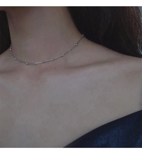 Vue détaillée d'un collier à billes en argent délicat porté sur le cou d'un mannequin femme