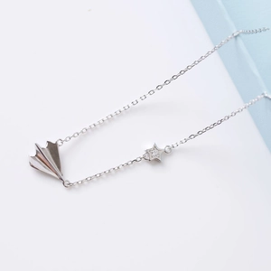 Detailed view of silver paper airplane and star pendant with sparkling cubic zirconia stone