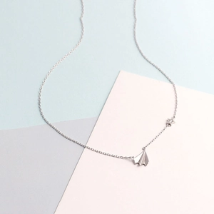 Macro view of 925 sterling silver paper plane and star charms on a delicate chain