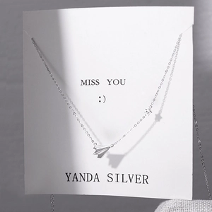 Minimalist 925 sterling silver paper plane necklace with small star pendant on display card