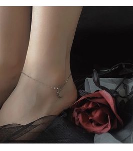 Detail of s925 silver crescent moon anklet with sparkling crystals on a woman ankle