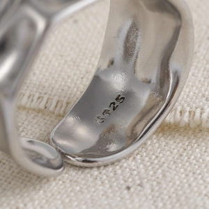 Macro shot of S925 sterling silver hallmark on an irregular wavy metal ring band