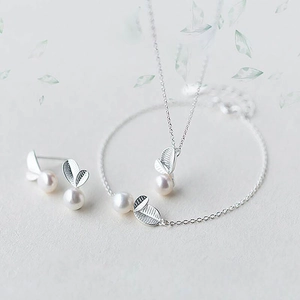Gros plan détaillé d'un ensemble de bijoux en argent s925 avec feuilles et perles blanches