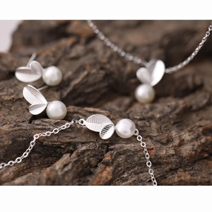 Vue macro d'une parure en argent S925 feuille et perles sur écorce naturelle