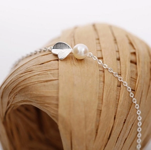 Détail du collier en argent S925 avec des feuilles en métal et une perle blanche fine