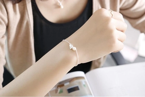 Détail d'un ensemble de bijoux papillon et perle en argent s925 dans une scène cosy
