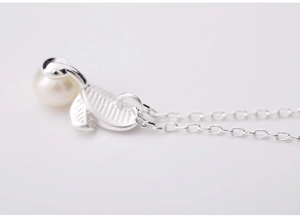 Détail macro d'un collier en argent S925 avec pendentif feuille et perle blanche sur chaîne O