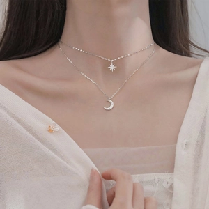 Detail view of 925 silver double layer necklace with star and moon charms on skin