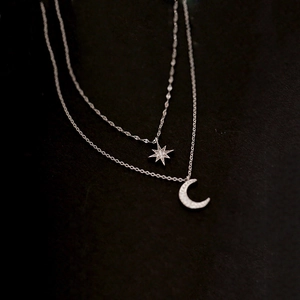 Detailed macro view of 925 sterling silver layered necklace with star and moon charms