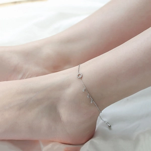 Close-up of S925 silver anklet with sparkling zircon circles on a soft white fabric background
