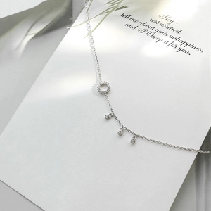 Close-up of 925 silver anklet with sparkling pavé zircon ring and three round pendants