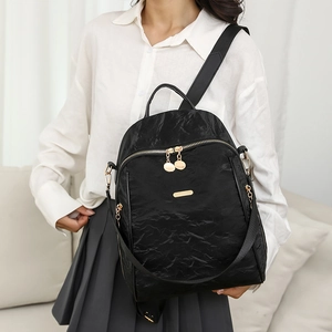 Fashionable black Oxford fabric backpack with gold zippers shown on model at home