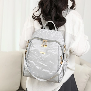 Close-up of light gray oxford backpack featuring metallic crinkle texture and gold zippers