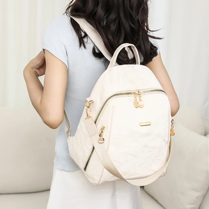 Creamy oxford fabric backpack with golden zippers shown on model in a home setting