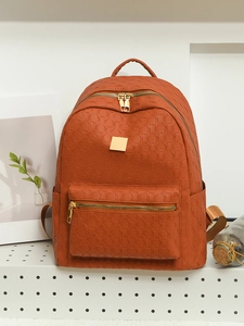 Detail of caramel brown PU leather backpack with geometric woven texture and gold zippers