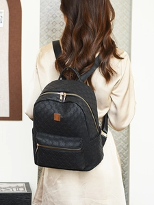Detail of black PU leather backpack with geometric texture and gold zipper on a model