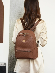 Detailed close-up of brown PU leather backpack with geometric hexagon embossing and gold zippers