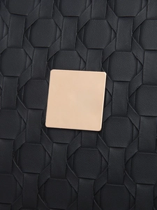 Macro shot of black woven leather texture with square gold metallic detail on backpack