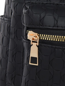 Macro view of geometric embossed black leather with premium gold metal zipper detail