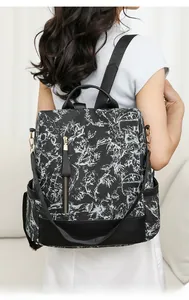 Détails d'un sac à dos noir pour femme avec imprimé floral et fermetures éclair dorées