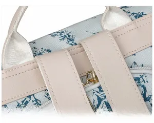 Détail d'un sac à dos floral bleu clair avec bretelles en cuir beige et zip doré