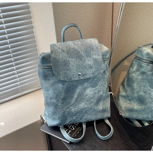 Detail view of a vintage gray-blue backpack with flap snap closure and textured finish
