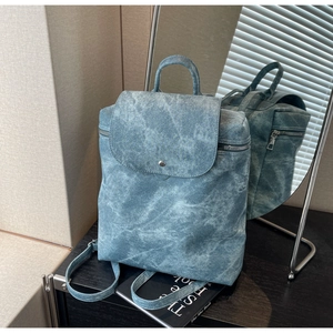 Detail view of the vintage blue acid-wash texture and silver buckle on this PU backpack