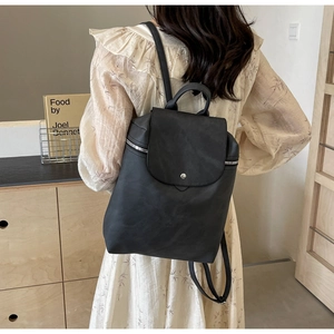 Detailed back view of a woman wearing a black PU leather backpack with magnetic closure
