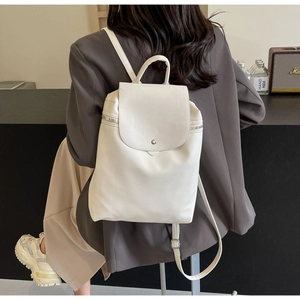 Detail of white PU leather backpack featuring metal snap button and decorative side zippers