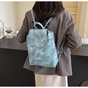 Back view of a light blue marble pattern PU leather backpack on a model wearing a blazer