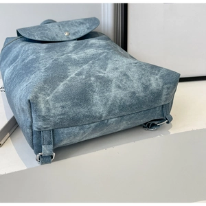 Detail shot of washed denim texture and silver metal hardware on this casual backpack