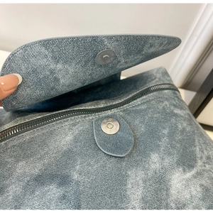 Detail showing blue washed denim texture with magnetic snap and silver hardware