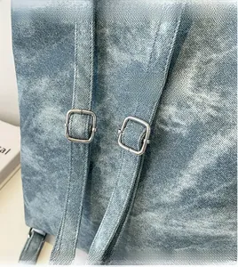 Detail of adjustable denim shoulder straps with silver square metal buckles on a backpack