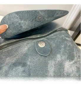 Detailed close-up of vintage silver magnetic clasp and zipper on blue denim backpack