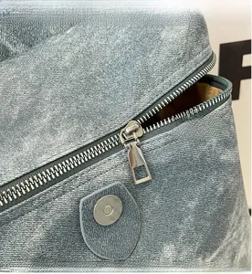 Close-up of light blue denim backpack with silver zipper and geometric magnetic buckle