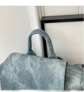 Detail of the top handle and washed denim texture on a light blue casual backpack