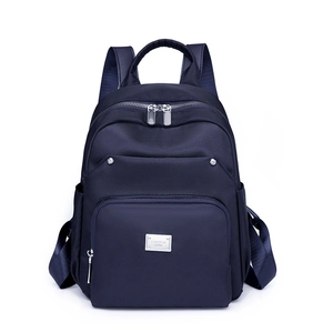 Minimalist navy blue nylon backpack with multiple pockets and silver brand logo plate