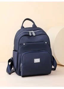 Detail view of navy blue nylon backpack with metal logo and multi-pocket storage layout